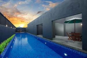 a large blue swimming pool with a table and an umbrella at The Tanjung Bidadari Seminyak in Seminyak