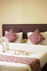 a bedroom with two beds with purple and white pillows at Hotel Kailas Residency Managed by Knight Hotels and Restaurants in Waluj Buzurg