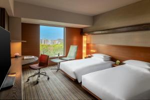 a hotel room with two beds and a desk and a window at Hyatt Regency Tokyo in Tokyo