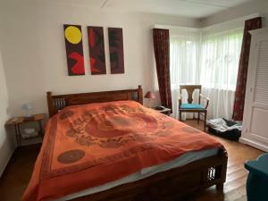 a bedroom with a bed with an orange blanket on it at Ferienhaus Tätendorf für die ganze Familie in Tätendorf-Eppensen