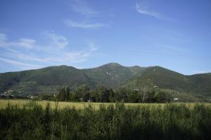 a green field with mountains in the background at La stamberga nel bosco in Asciano Pisano +8 photos