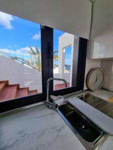 a kitchen with a sink and a window with a clock at B16 caleton blanco in Puerto del Carmen