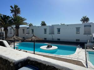 a swimming pool in front of a building with palm trees at 42 Guacimeta Club in Los Pocillos