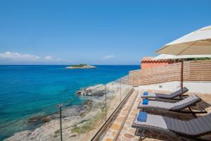 a balcony with chairs and an umbrella and the ocean at Kokkinos Studios With Pool & Sea View, by ZanteWize in Skinária