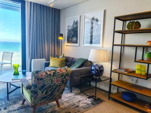 una sala de estar con un sofá y una mesa en Wavescape Chic Seaside Stay, en Muizenberg