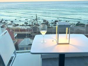 una copa de vino en una mesa con vistas al océano en Wavescape Chic Seaside Stay, en Muizenberg
