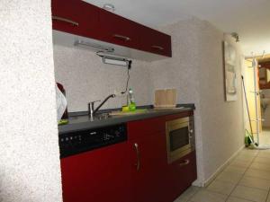 eine rote Küche mit Spüle und Mikrowelle in der Unterkunft 2 Einbettzimmer in Neubrandenburg