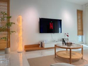 a living room with a table and a tv on a wall at MokuMoku Miri Homestay FOC Netflix & Ytb 18pax in Miri