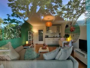 a living room with a couch and a tree on the wall at FlamingoSuite 6 min zum See in Herrsching am Ammersee