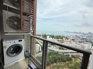 a balcony with a washing machine and a view of a city at Condo Sea view Beach U25 in Pattaya South