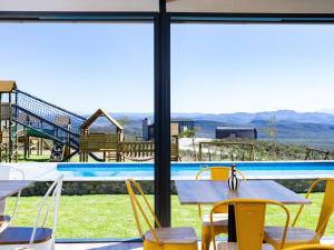 Una vista de una piscina desde un restaurante con mesas y sillas. en Goats Window Luxury Safari Lodge, en Bonnievale