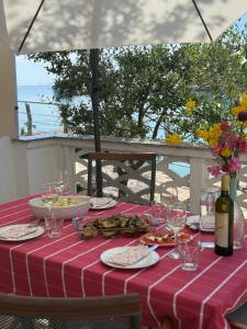 a table with a red and white table cloth with food and wine at Kuća Ugor in Lun