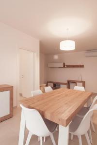 a dining room with a wooden table and white chairs at Alessia in wonderland in Alghero