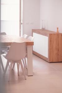 a wooden table with white chairs and a wooden table at Alessia in wonderland in Alghero