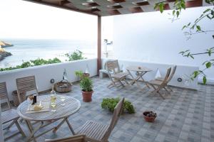 a patio with tables and chairs and a view of the ocean at Primrose Apartments in Astypalaia