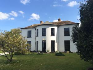 a large white house with a tree in the yard at Laston House in Ilfracombe