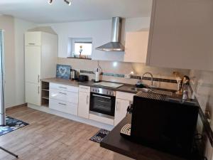 a kitchen with white cabinets and a stove top oven at Ferienwohnung Sonnenwinkel in Scheiden