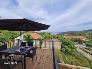 a wooden deck with a table and an umbrella at Apartment Zaglav in Zaglav