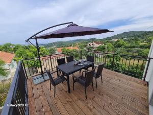 a table with chairs and an umbrella on a deck at Apartment Zaglav in Zaglav +5 photos