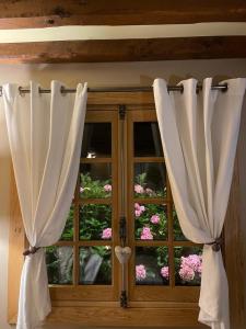 een raam met witte gordijnen voor bloemen bij La Moutinière, luxury cottage with pool in Manerbe