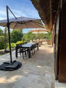 een tafel en stoelen met een parasol op een terras bij La Moutinière, luxury cottage with pool in Manerbe