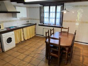 a kitchen with a table and a washing machine at La Cerezal II in Borines