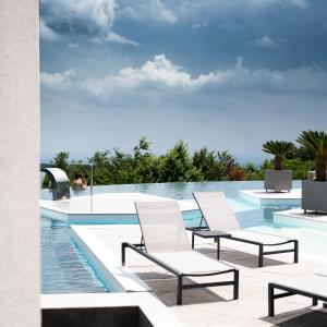 grupa krzeseł ustawionych obok basenu w obiekcie Hotel Ózon & Luxury Villas w mieście Mátraháza