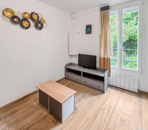 a living room with a flat screen tv and a table at Confort & calme proche Marne in Champigny-sur-Marne
