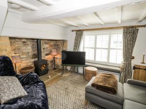 a living room with a couch and a tv and a fireplace at Cotstone Cottage in Chipping Campden