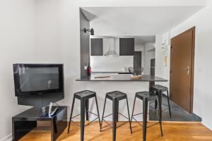 Una cocina con cuatro taburetes negros y un televisor. en T3 Appartement au centre ville, en Annecy