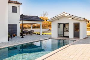 a home with a swimming pool and a house at Villa Vilma-house with heated pool & garden in Trilj