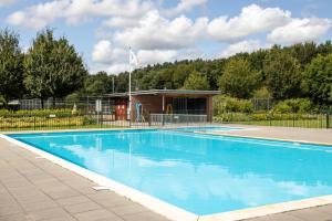 a large blue swimming pool in front of a building at Ruime vakantievilla in Zeewolde in Zeewolde