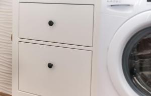 a laundry room with white cabinets and a washing machine at House Victoria 2 by Villas Guide in Nerezine