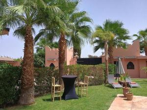 a yard with chairs and palm trees and a house at Villa Essalah & Spa in Marrakech