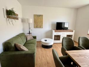 a living room with a green couch and chairs at Komfortables Innenstadt-Apartment WOLF - Zentrumlage in Sankt Pölten