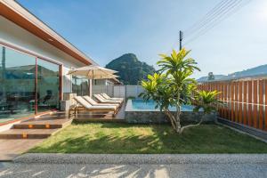 ein Haus mit Pool und Terrasse mit Stühlen und Sonnenschirm in der Unterkunft New Pakbia Private Pool Villa 3 Bed Ao Nang Krabi in Ban Chong Phli