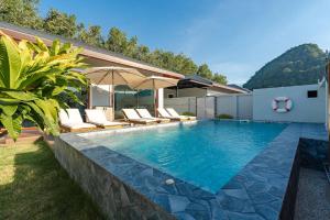 ein Swimmingpool mit Stühlen und Sonnenschirmen neben einem Haus in der Unterkunft New Pakbia Private Pool Villa 3 Bed Ao Nang Krabi in Ban Chong Phli