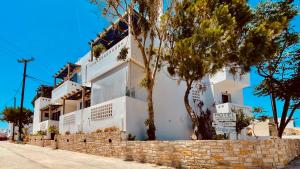 Un edificio blanco sobre un muro de piedra con árboles. en Angelica's Deluxe Rooms in Adamas, en Adamas