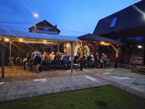 a group of people sitting at tables on a patio at night at Pensiune Matrix in Curtea de Argeş