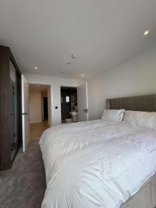 a bedroom with a large white bed and a bathroom at The Banks - Private Luxury 2-Bed Flat Manchester Central in Manchester +2 photos