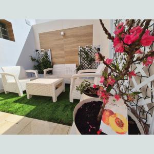 taras z białymi wiklinowymi krzesłami i różowymi kwiatami w obiekcie Cozy Chalet - playa a 200m w mieście Chiclana de la Frontera