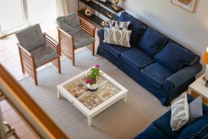 ein Wohnzimmer mit einem blauen Sofa und Stühlen in der Unterkunft Pita's House - Villa Sagres 2 in Sagres