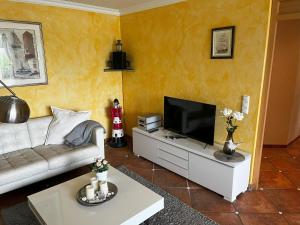 a living room with a couch and a flat screen tv at Im Aida Park im Nordseebad Tossens liegt dieses geräumige Ferienhaus im mediterranen Stil. in Butjadingen OT Tossens