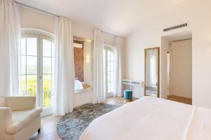 a white bedroom with a white bed and a chair at Villa Delle Vigne in San Venanzo +32 photos