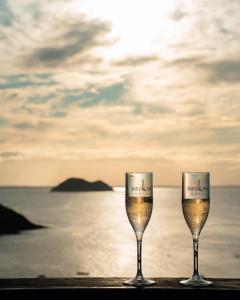 two glasses of wine sitting on a table near the ocean at Buzios Mar Hotel in Búzios