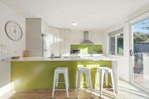 une cuisine avec des murs blancs et verts et des tabourets dans l'établissement Spacious Modern Home, à Lindisfarne 38 autres photos
