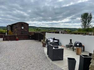 a patio with chairs and a fireplace on a roof at The Stables in Gloucestershire