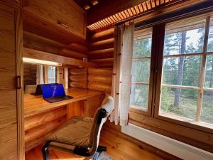 ein Zimmer mit Schreibtisch und Laptop in einer Blockhütte in der Unterkunft Villa Pihlajanmarja is a Stunning Log Villa on a Waterfront Estate in Långstrand