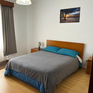 a bedroom with a large bed with blue pillows at Tiny apartment near the airport in Ponta Delgada