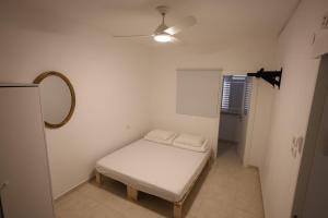a small room with a bed and a ceiling fan at Vacation rental in Netanya